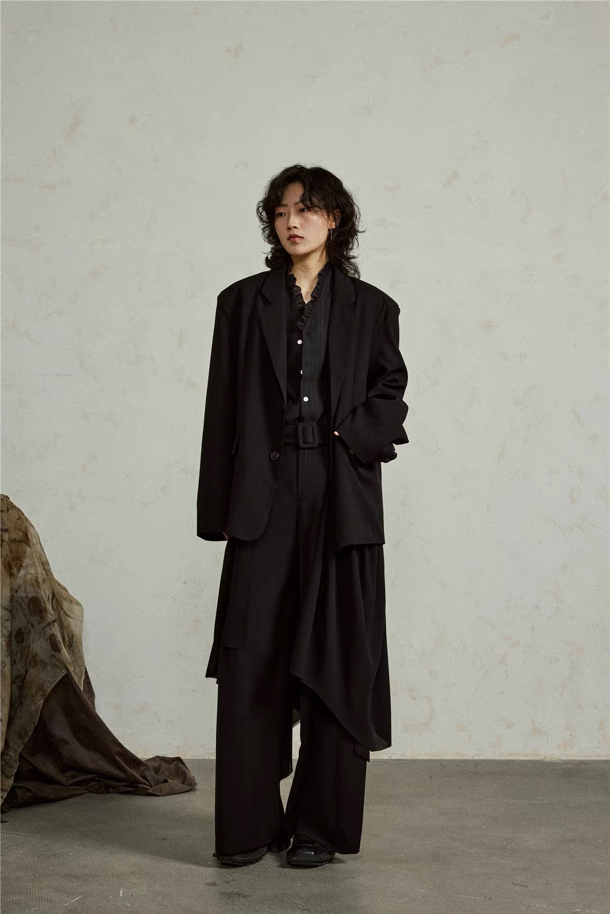 Full-length three-quarter view of the black blazer and flowing side panel