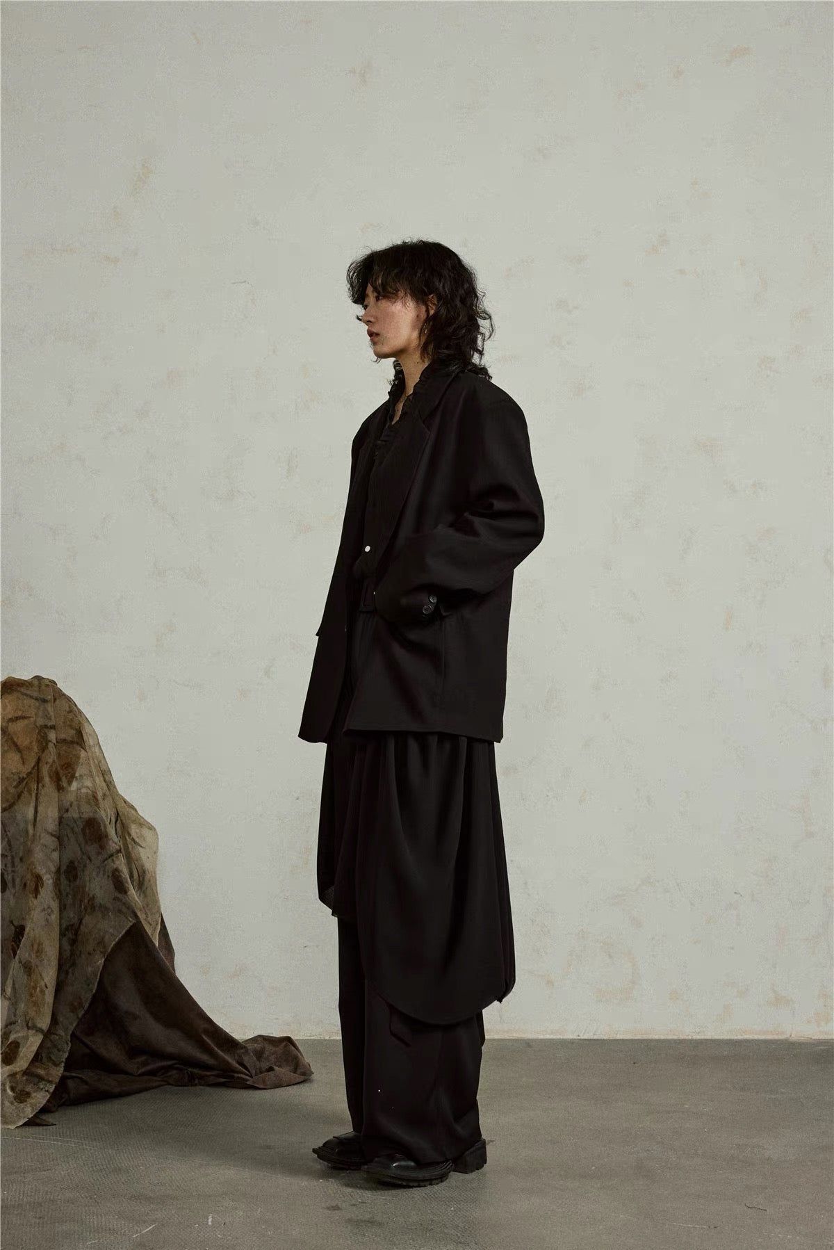 Side view of the black blazer showing its long layered silhouette