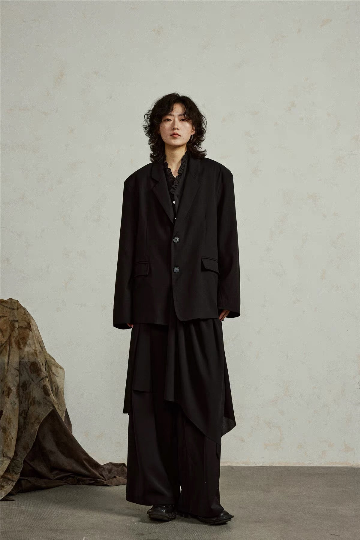Full-length front view of the black blazer with its asymmetric draped hem