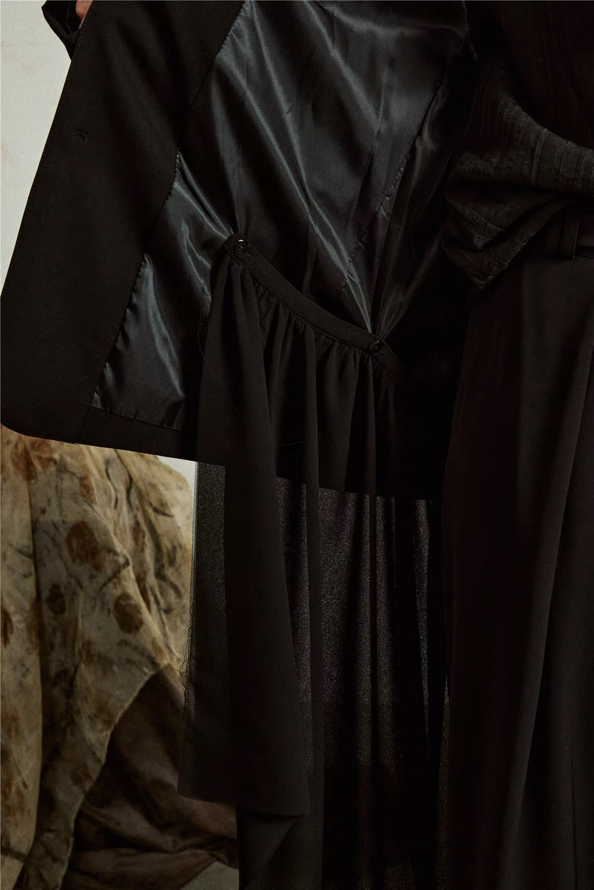 Interior close-up of the black blazer showing the detachable hem fastening straps